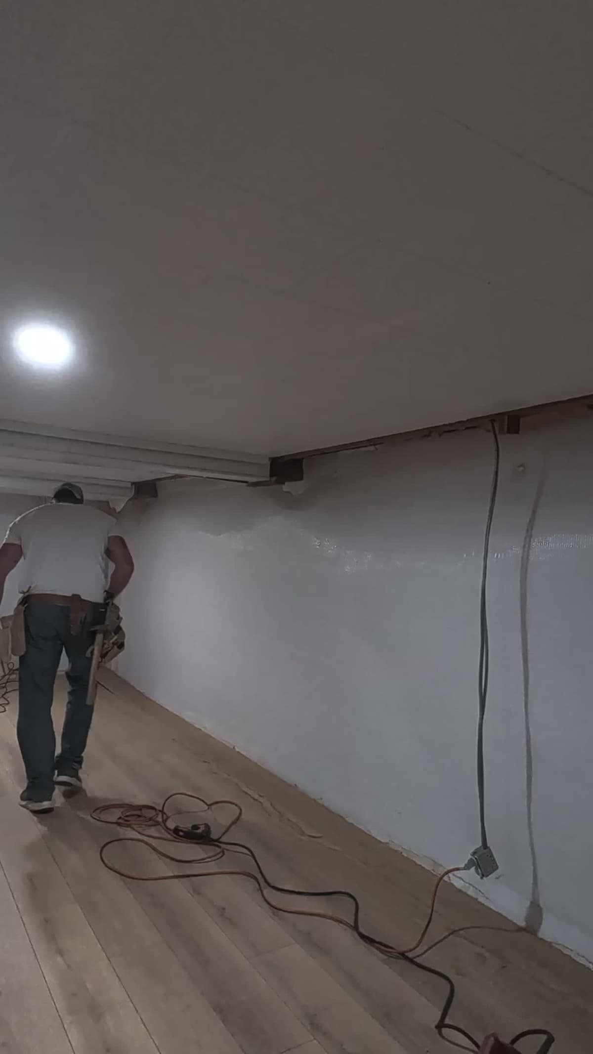 The same basement mid-build, bare drywall and extension cords