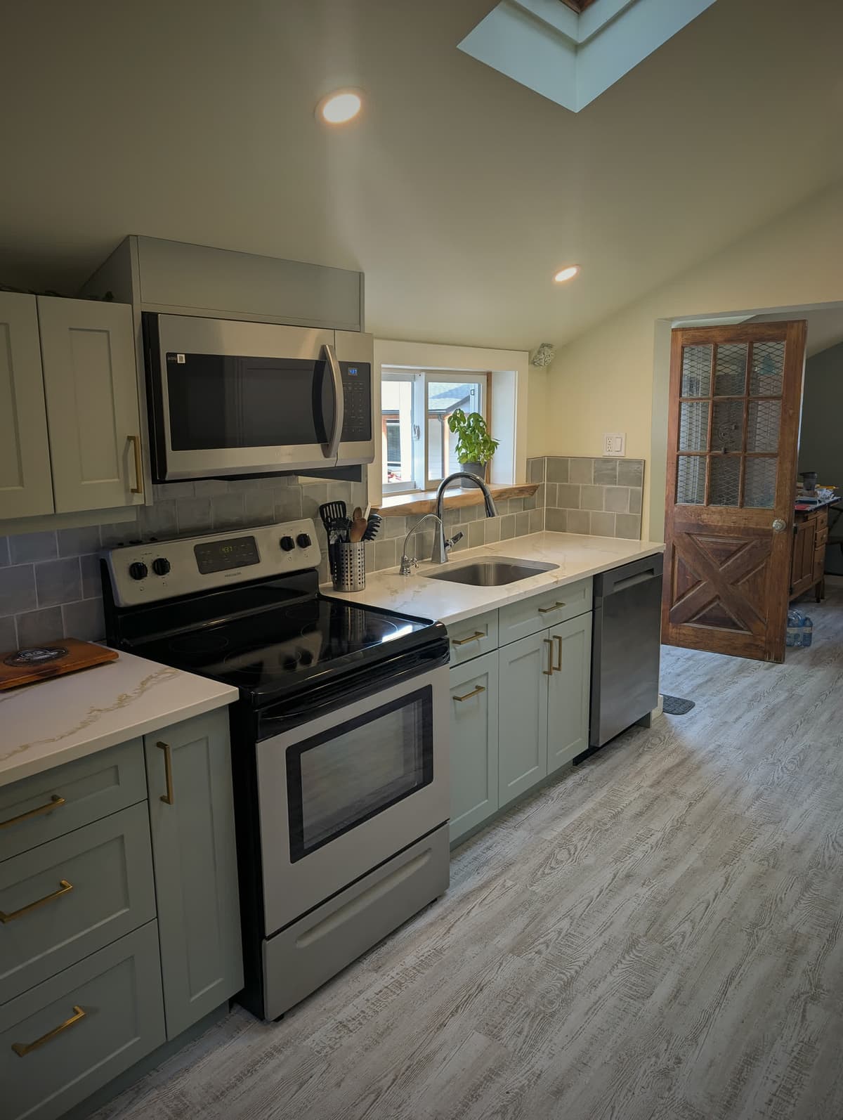 Finished century home kitchen with sage green cabinets, quartz counters and brass hardware